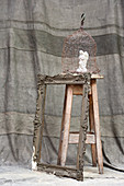 Angel figurine in cage on wooden stool and antique picture frame
