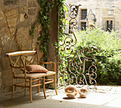 Bistro-style wooden bench against stone wall and next to ornate metal grille