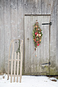 Festive teardrop wreath of conifer branches and baubles on door