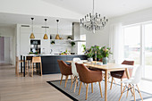 Wooden table and classic chairs in dining area next to kitchen in open-plan interior