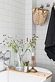 Candlestick and vase of grasses on wooden bath caddy