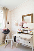 White bureau, rocking chair and pastel wallpaper in girl's bedroom