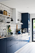 Contemporary kitchen with blue cabinets and white-tiled wall