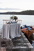 Gedeckter Tisch auf einem Steg und Boot auf einem See