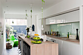 White, high-gloss cupboards and pale wooden island counter in modern kitchen