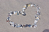 Love-heart formed from pebbles on sand