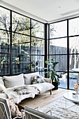 Beigefarbenes Sofa vor Fensterfront zum Terrassen- und Gartenbereich