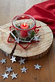 Candle in jar on wooden board in rustic star made from nails and felt yarn