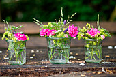 Bouquets of roses, lady's mantle and meadow flowers in canning jars