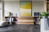 Large artwork above sideboard in open-plan living room with tiled floor