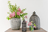 Lilac and spirea in antique vase and lanterns on wooden table