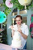 Nadja Bruhn decorating three-tiered cake in biscuit workshop