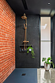 Black bathroom with red brick wall and walk-in shower area