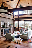 Sitting area by the fireplace in an open living room of an architect's house with a high wooden ceiling