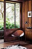 Shell chair made of wood next to an open sliding door to the enchanted garden area