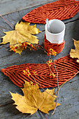Selbstgestrickte Tassenwärmer und Tischläufer in Blätterform als herbstliche Tischdeko