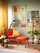 Painting on wall above orange armchair and matching footstool