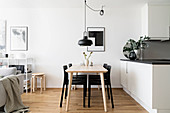 Black chairs at dining table and kitchen in open-plan interior