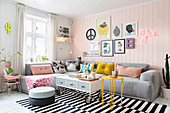 Grey corner sofa with scatter cushions in living room with pink wooden wall