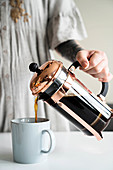 Kaffee wird aus einer French-Press in eine Tasse gegossen