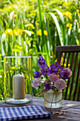 Kleiner Blumenstrauß und Windlicht auf Gartentisch