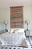 Oriental rug on wall above bed with quilted bedspread