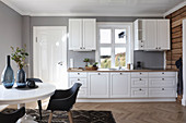 Modern, white, country-house kitchen with dining area and grey walls
