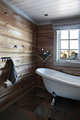 Wooden walls and free-standing bathtub in rustic bathroom