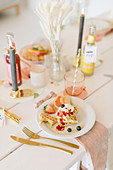 Waffles with fruit and cream on festively set table