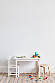 Colourful building blocks on and next to child's table with chair and stool