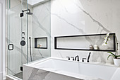 Badezimmer in Marmor-Ausführung mit Badewanne und Duschkabine aus Glas