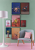 Blumenbilder an grüner Wand, davor Stehlampe, Beistelltisch und Sessel