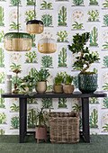 Houseplants on table against plant-patterned wallpaper