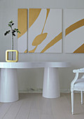 White table with organic shape, single rose in vase and triptych artwork