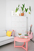 Sofa, white metal filing cabinet and pink coffee table and guitar