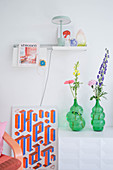 Vases of flowers, picture leaning against wall and ornaments on shelf providing accents of colour