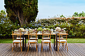 Table festively set with hydrangeas and candle lanterns on wooden deck