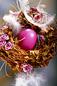Easter nest decorated with pink flowers and feathers
