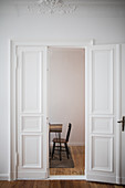 Open panelled doors in period apartment with view of chair and table