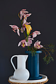 Vase of boat orchids, calla lily and pine branch