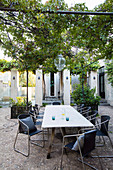 Langer Tisch auf der Terrasse mit Pergola im sommerlichen Innenhof
