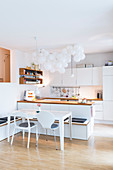 Cloud of white balloons above island counter in bright, open-plan kitchen