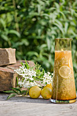 Fresh elderflower juice in a glass carafe decorated with elderflowers