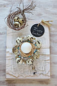 Wreath of beads and quail eggs on book with torn pages