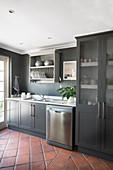 Grey kitchen counter with glass-fronted cupboards and plate rack