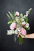 Hand holding early summer bouquet in pastel shades