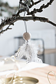 Angel handcrafted from wooden bead and feathers hung from gnarled branch