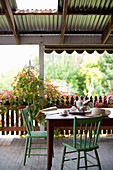 Esstisch mit grün gestrichenen Holzstühlen auf überdachter Terrasse
