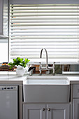 Kitchen counter with sink below window with closed louvre blinds