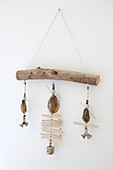 Mobil made from shells, wood and little bells hung on white wall